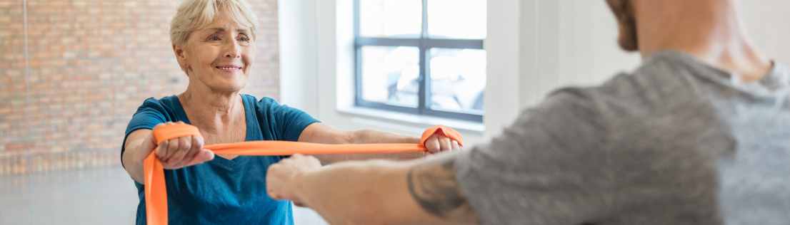 Senior woman working with a personal trainer using resistance bands