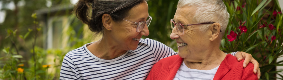 2 senior women outdoors hugging